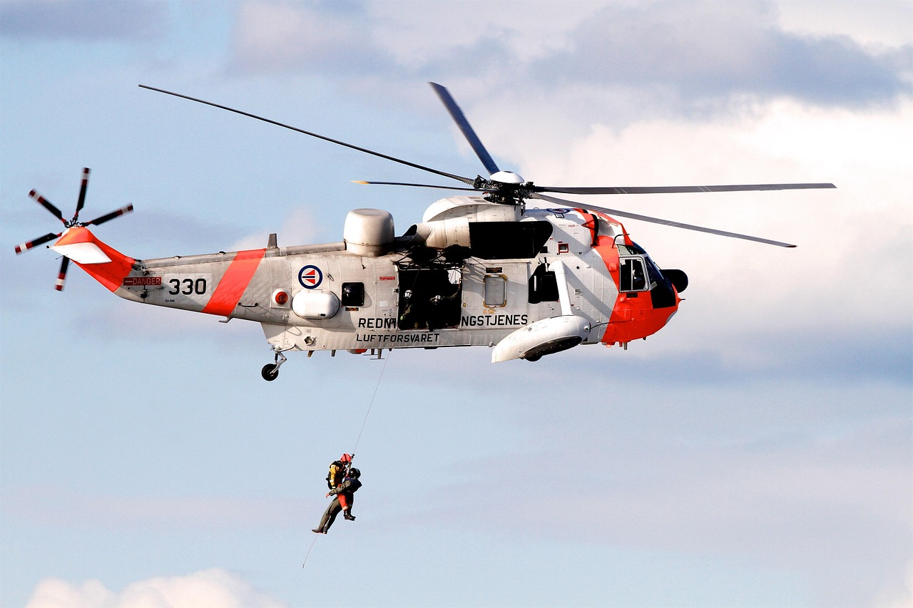 A search and rescue helicopter winching people beneath it against a blue sky.
