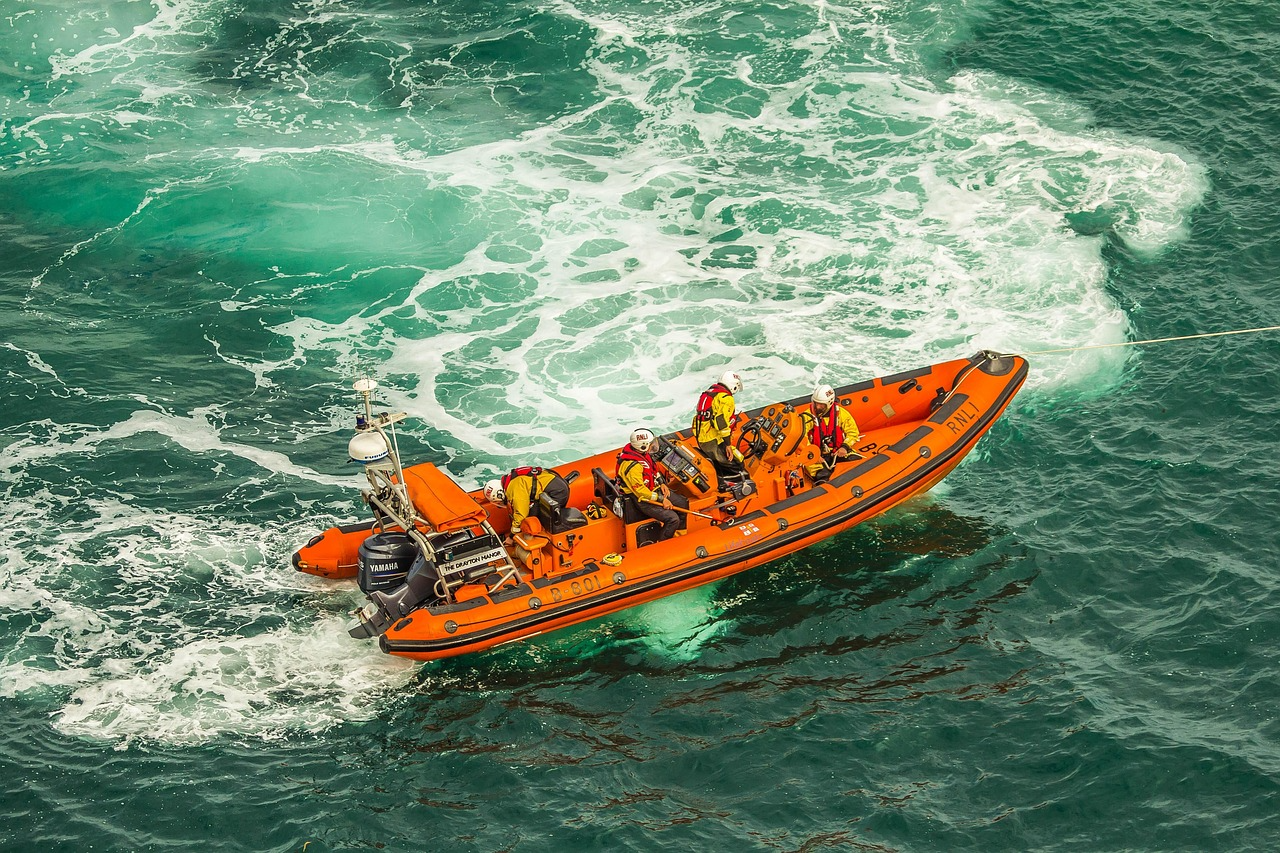 An orange RNLI lifeboat carrying rescuers through green sea and white surf.